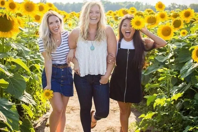 Three woman standing between sunflowers