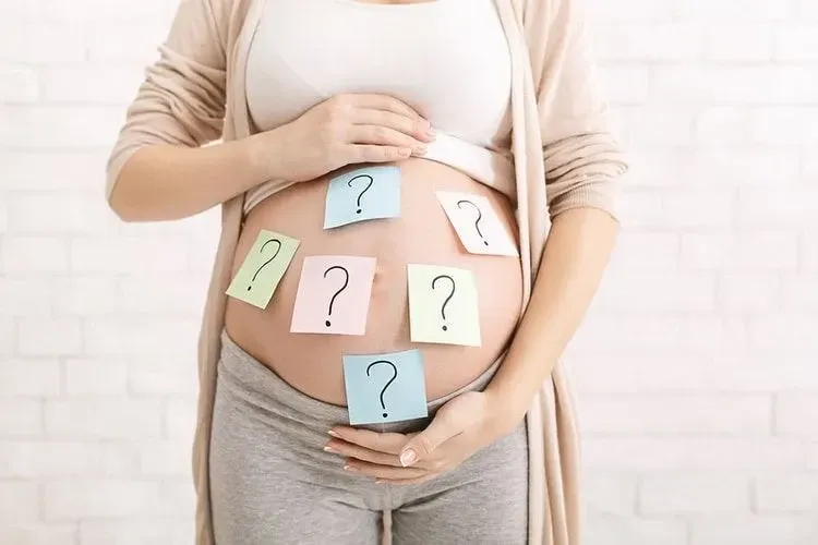 Sticky notes with question marks stuck on a woman's pregnant belly