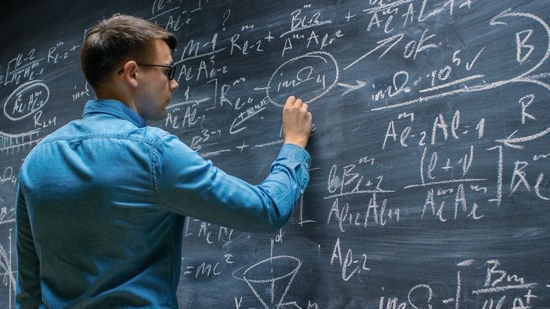 Mathematician solving maths problems on a blackboard