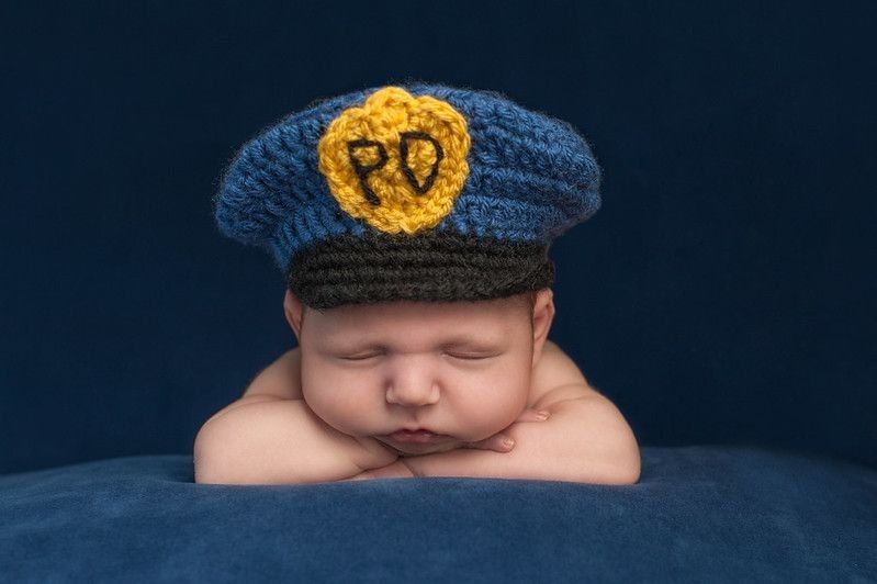 Newborn baby wearing police officer hat