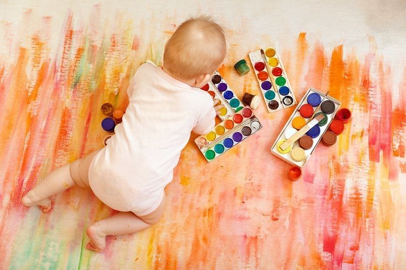 The child is smeared with paint on a light background