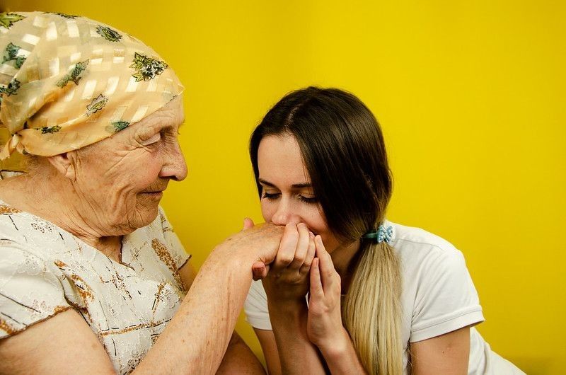 Granddaughter kissing grandmother's old hand close-up representing respect