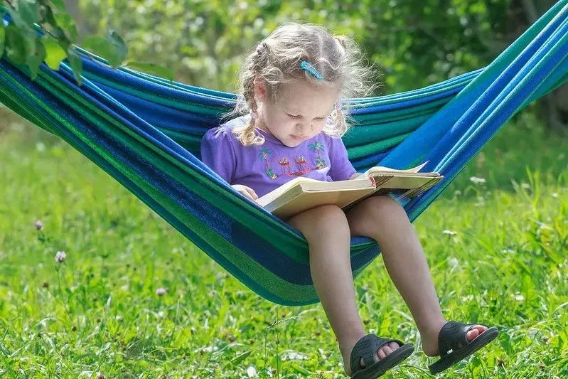 Child reading outside in a hammock
