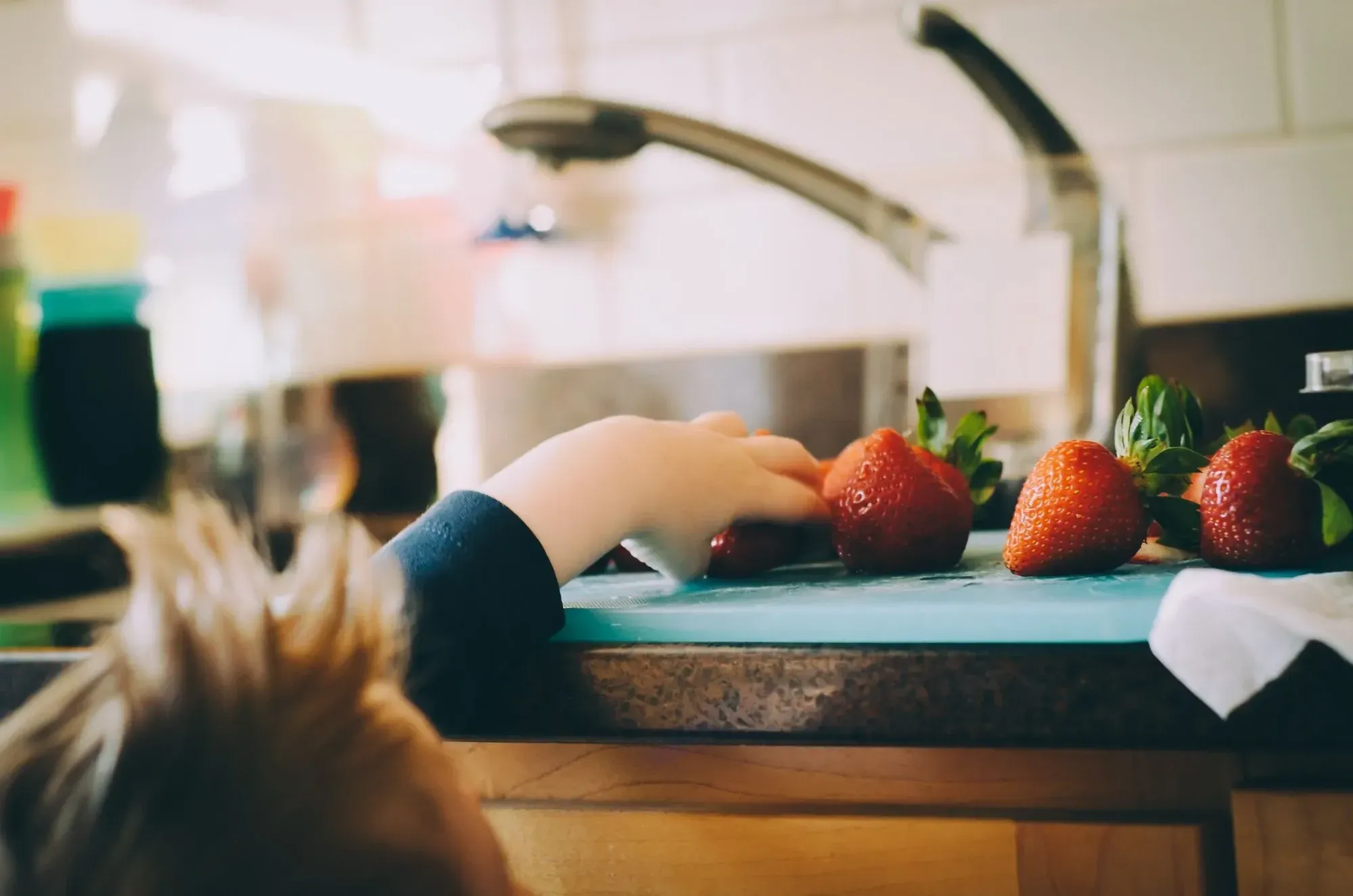 child taking strawberries from counter 