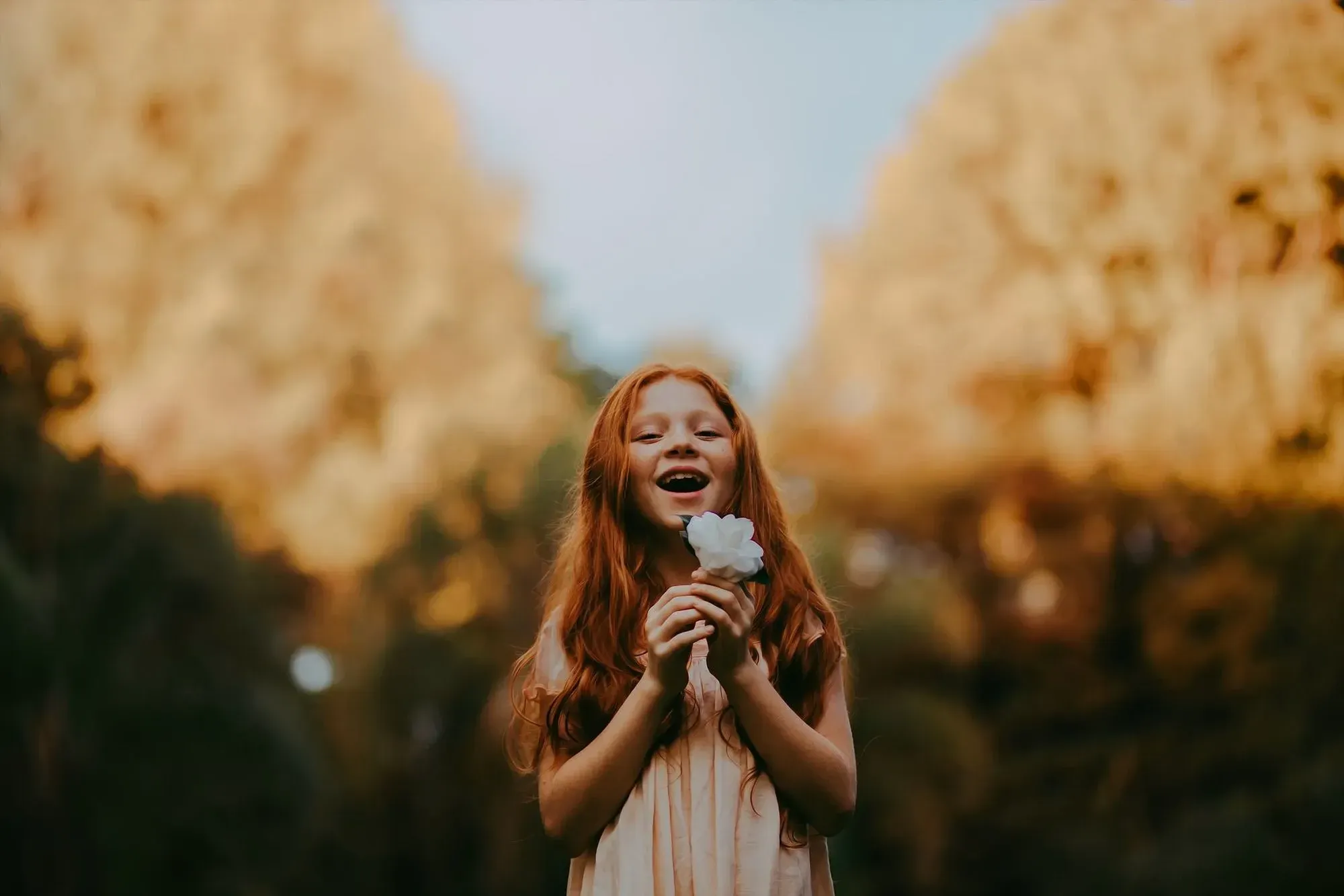 little girl laughing while holding a flower