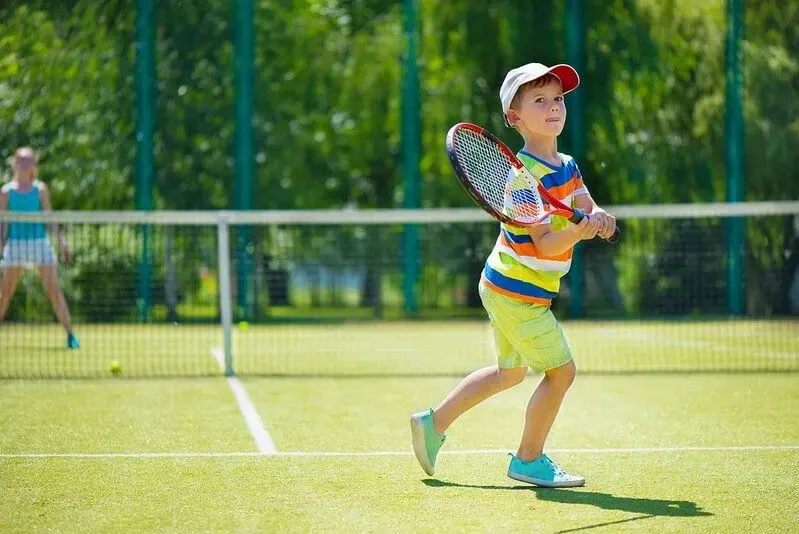 Child playing tennis while thinking of tennis jokes
