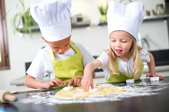 Two young kids cooking food at home.