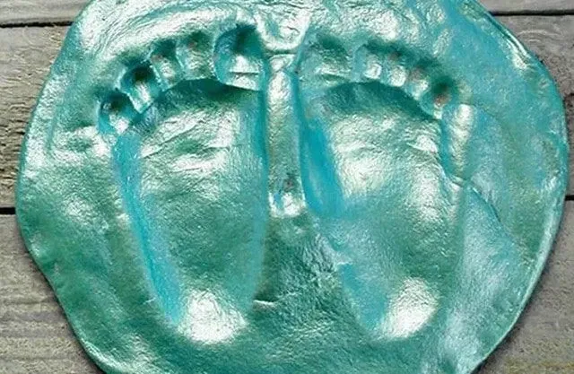 A foot print ornament with two baby size feet in green salt dough.