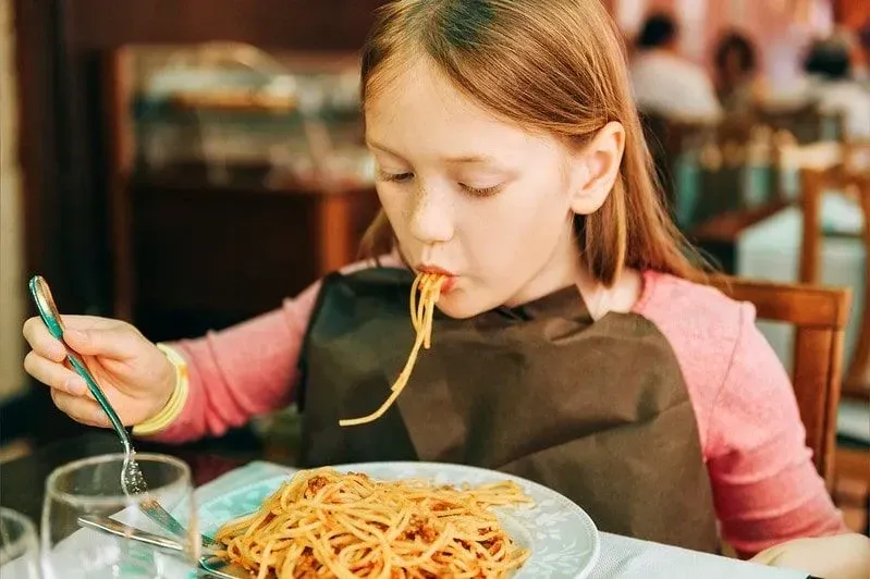 Girl eating spaghetti at a child-friendly restaurant