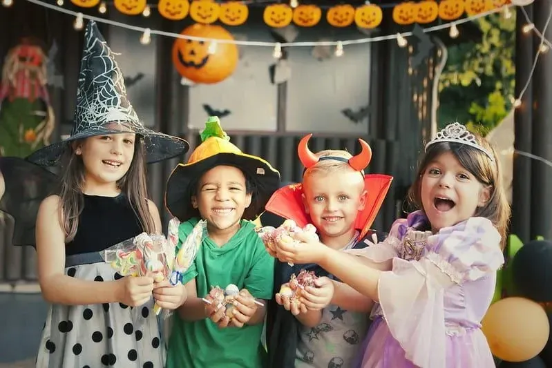 Four children in Halloween costumes are having fun at a Halloween party.