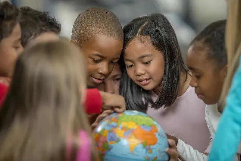 Group of children looking intently at a colourful globe.