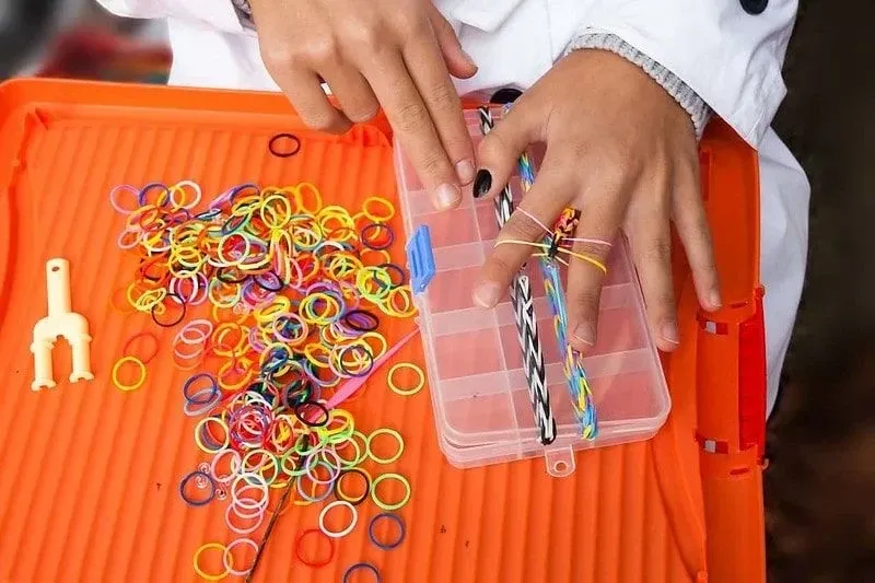 Hand Making Bow Out of Loom Bands On Orange Desk