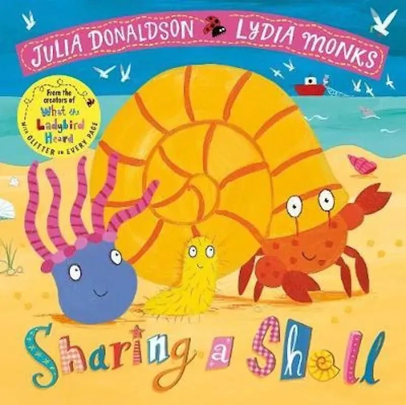 Cover of Sharing A Shell: two sea creatures and a red crab stand on the beach smiling. There is a large shell on the red crab's head and the ocean is in the background.