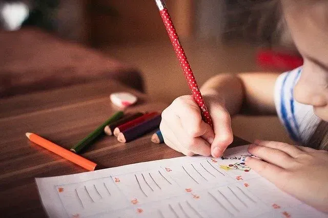Little girl drawing on her worksheet.