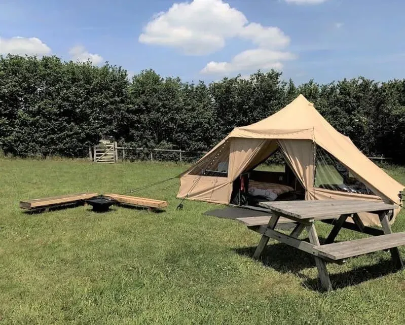 Luxury tent at Arniss Bell Tents with a bell inside and picnic table outside.