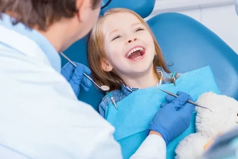 Young girl sat in the dentist's chair laughing.