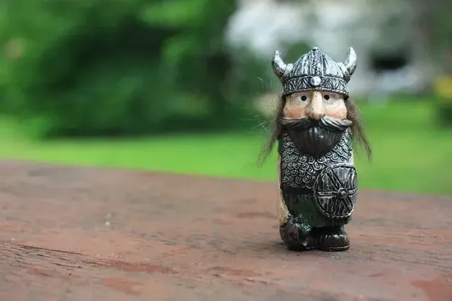Toy of a miniature Viking man, with a typical Viking helmet carved, on a table.