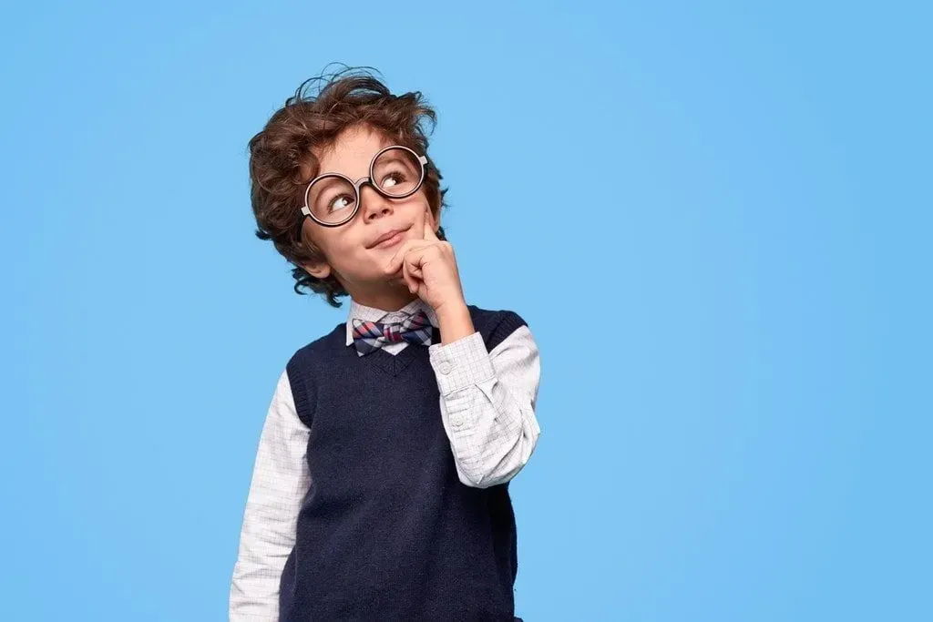 Young boy dressed smartly wearing glasses, looking pensive.