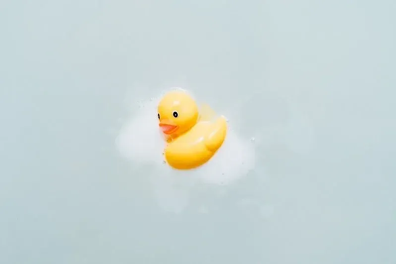 Yellow rubber duck with soapy foam on it.