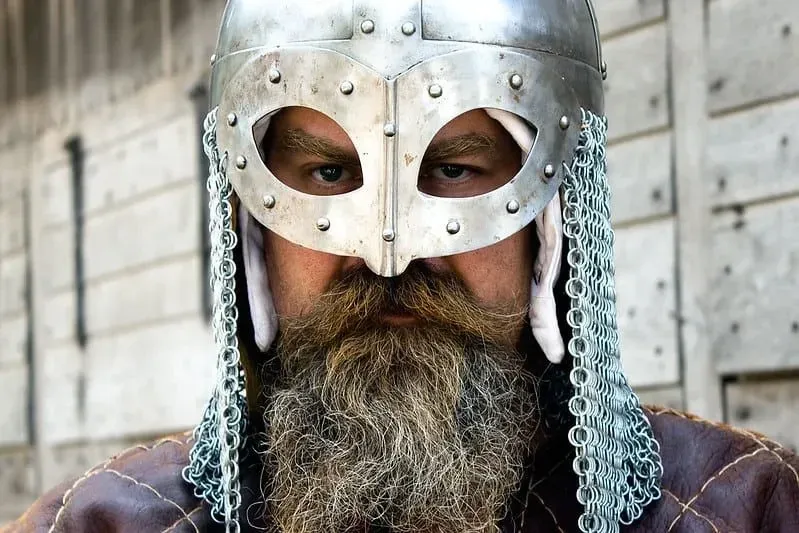 A man wearing a silver Viking helmet with chain mail on either side.