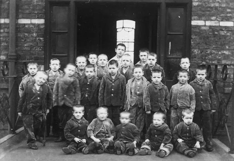 Black and white photo of children standing in front of the Victorian workhouse.