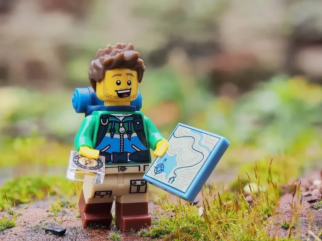 A Lego explorer holding a lego map and compass.