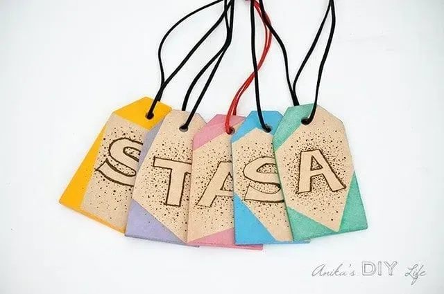 DIY wooden luggage tags, decorated with letters drawn on them.