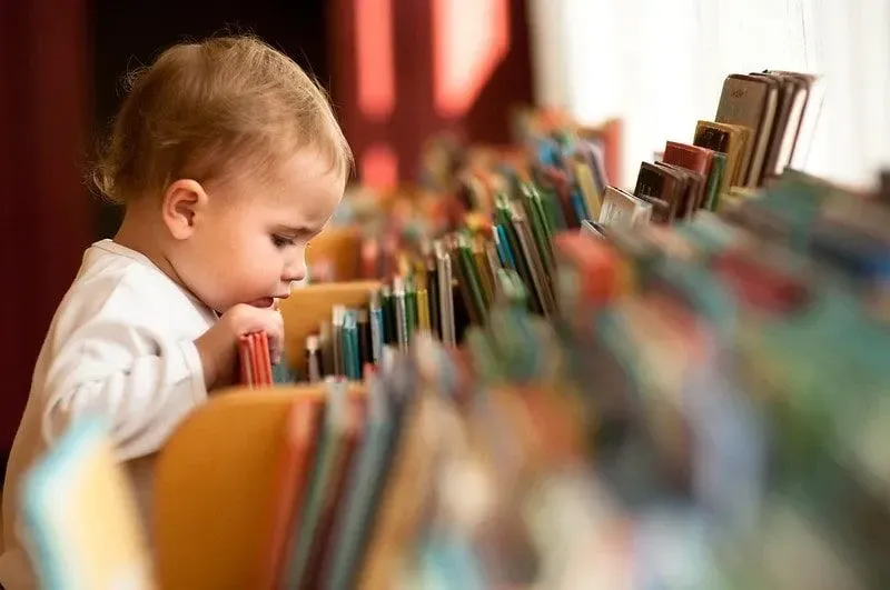 Toddler flicking through books in the library.