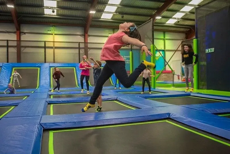 Girl making a pose in the air as she bounces on the indoor trampolines.