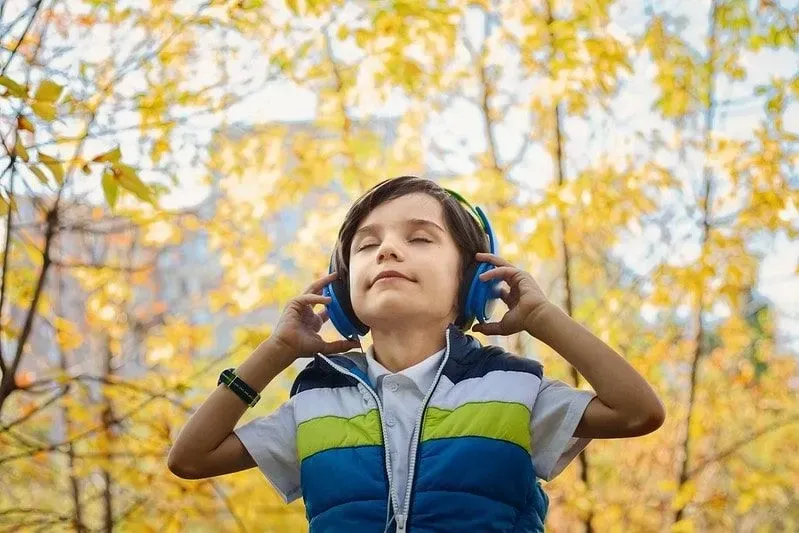 Boy wearing headphones while walking in the park.