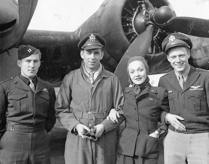 Marlene Dietrich and RAF pilots standing in front of a bombardment plane.