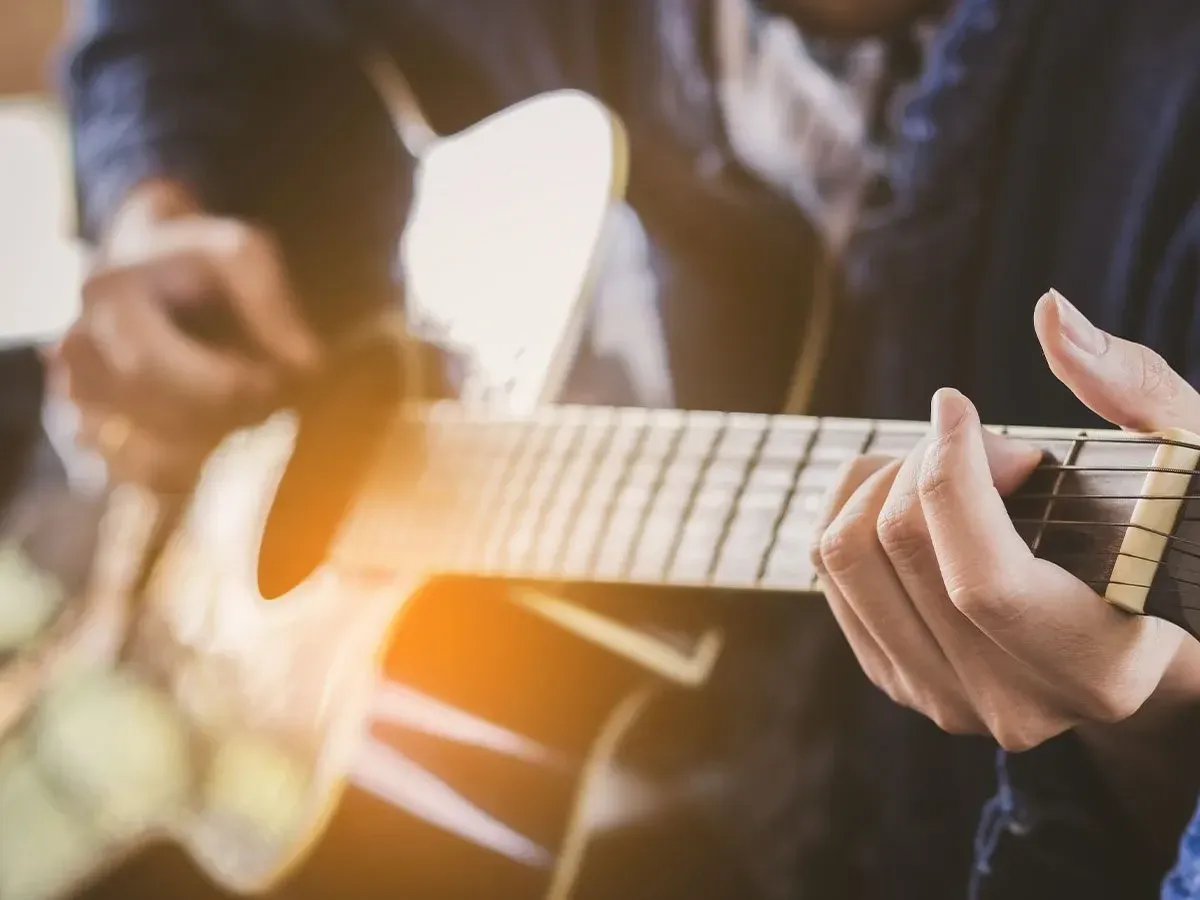 A close up image of a teenager playing the guitar as a hobby.