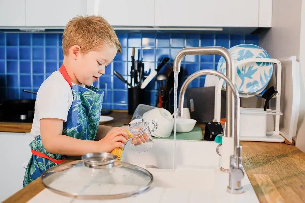A young boy doing some washing up to earn a reward from his DIY reward chart.