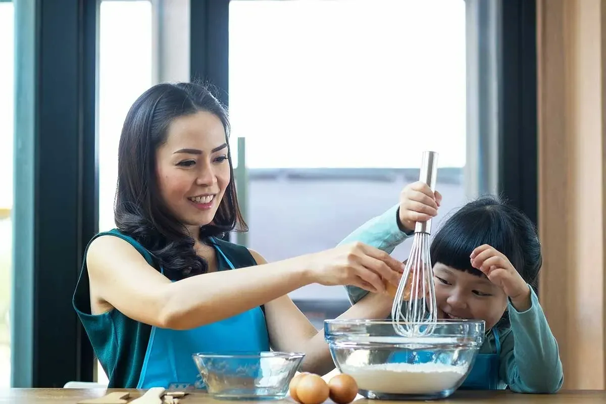 A mother and her child whisking ingredients together in the kitchen to make a gravity cake.