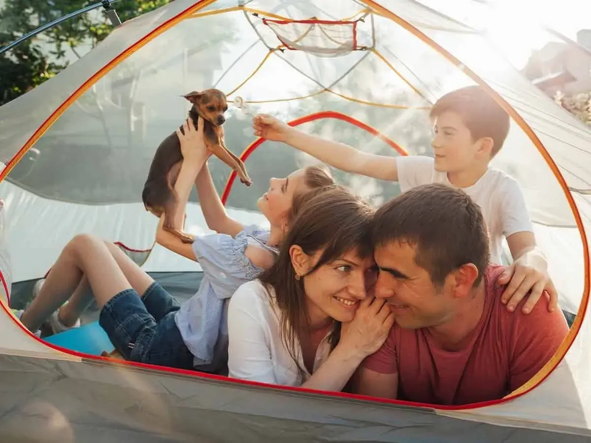 Happy family lying in their camping tent together with their dog.