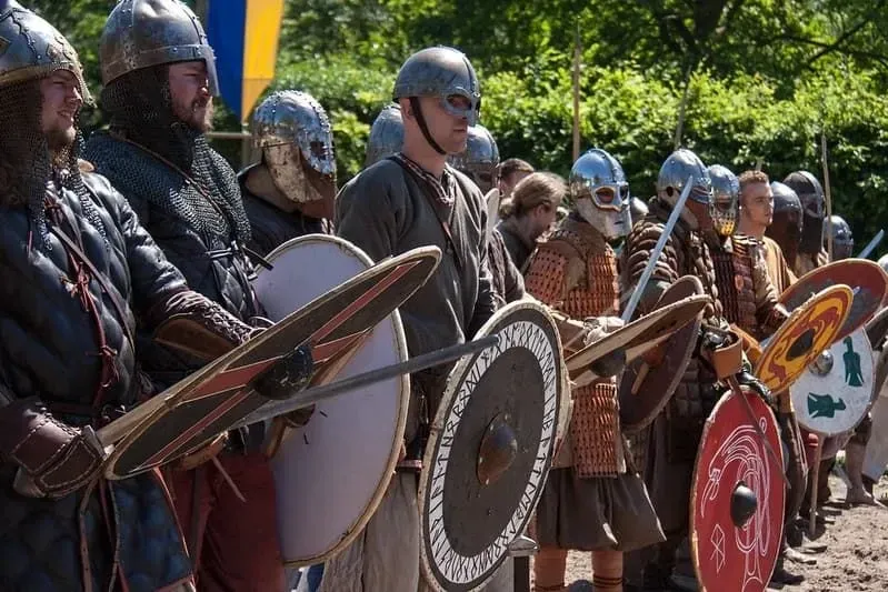 A Viking army dressed in armour and carrying swords and Viking shields.