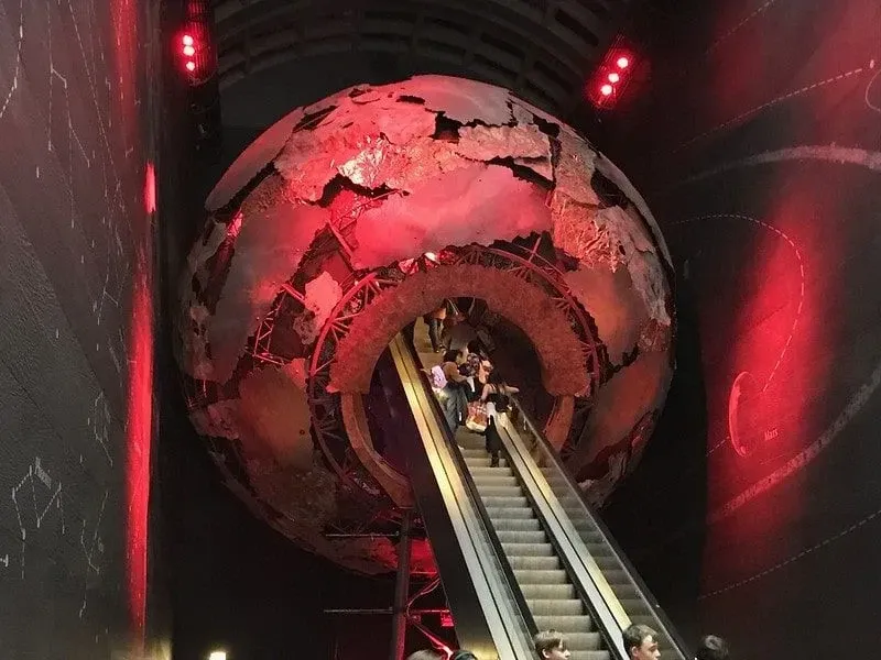 Escalator going up through a model of the planet. 