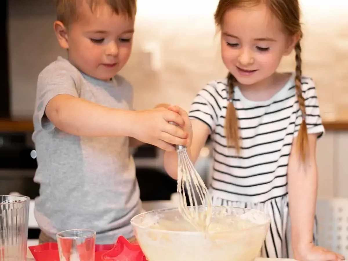 Little girl and boy in the kitchen making a dragon cake.