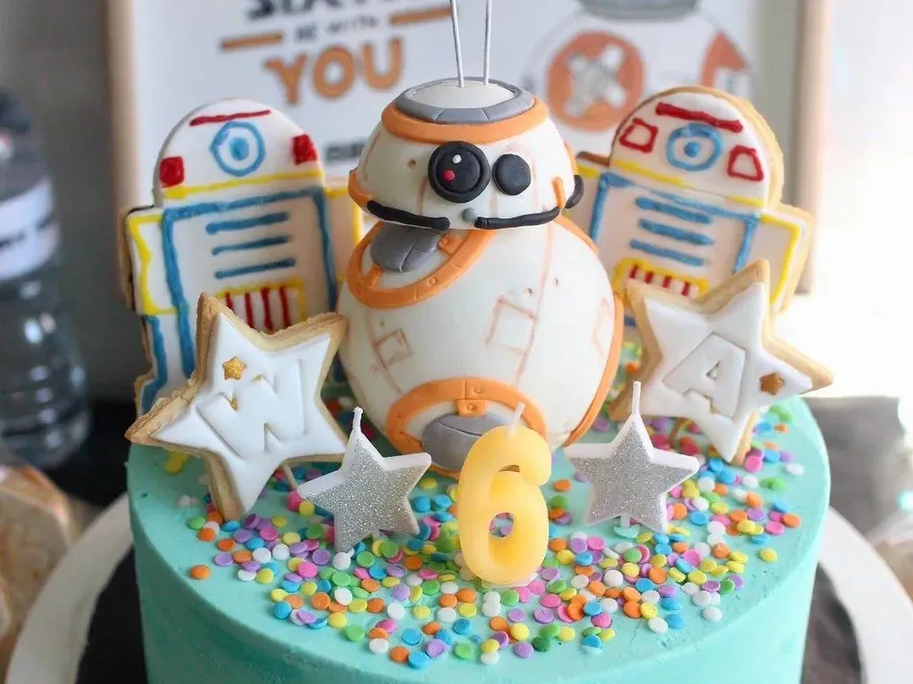 A colourful Star Wars birthday cake with a Star Wars cake topper on top.