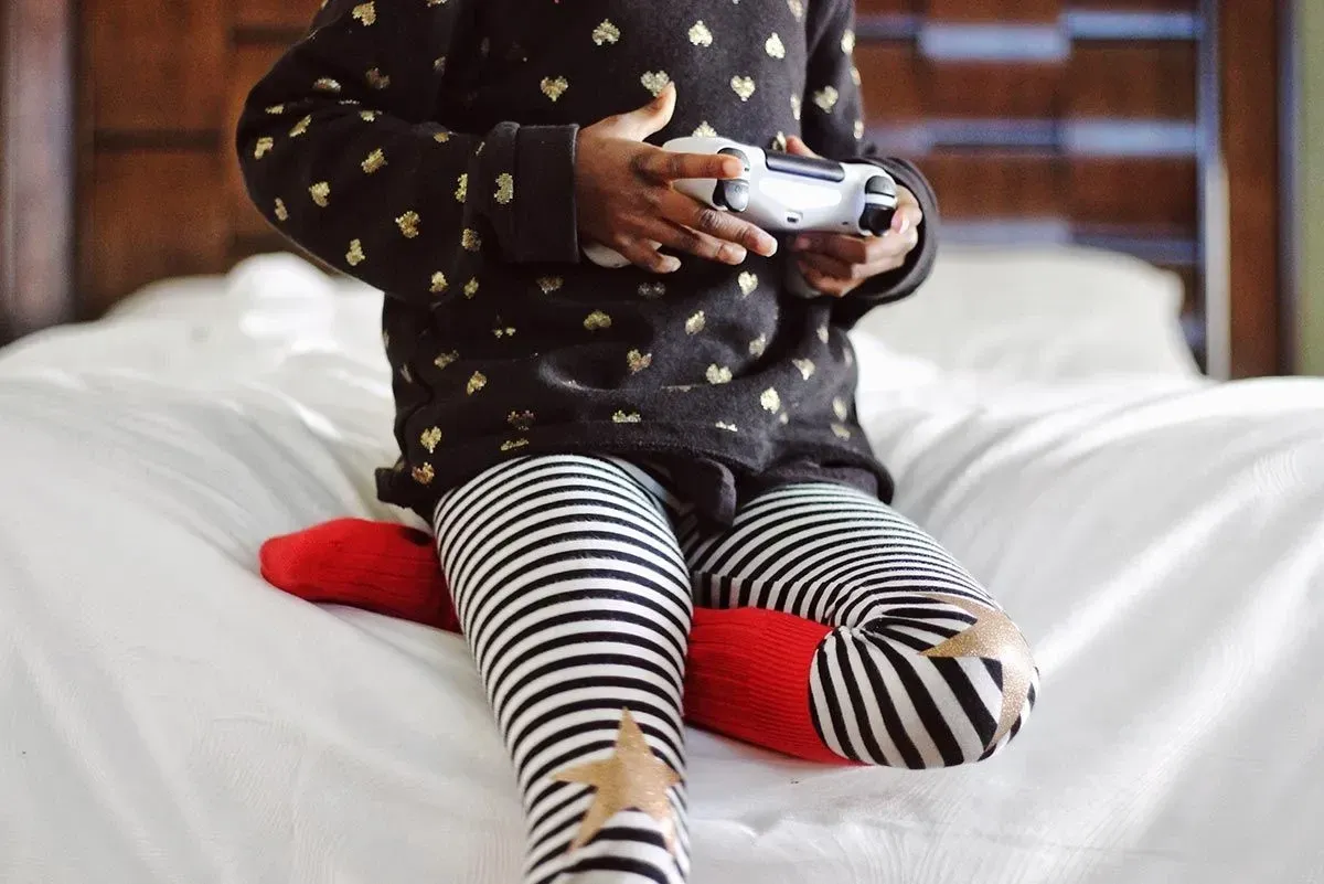 Close up of a child holding a games console controller, playing Fortnite.