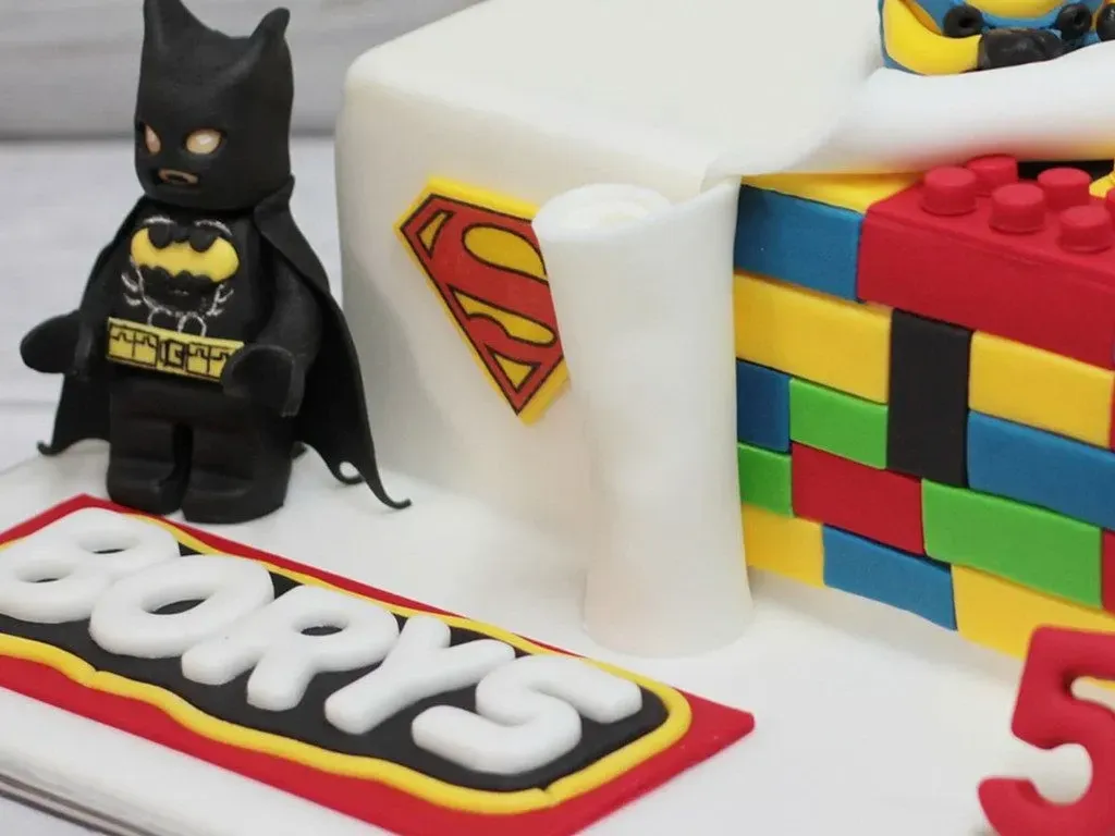 A close up image of a Batman figure next to a cake covered in fondant icing.