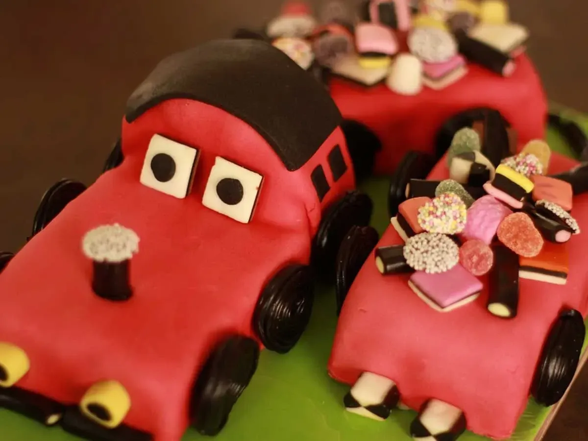 Cake in the shape of a red car with sweeties decorating it on top.