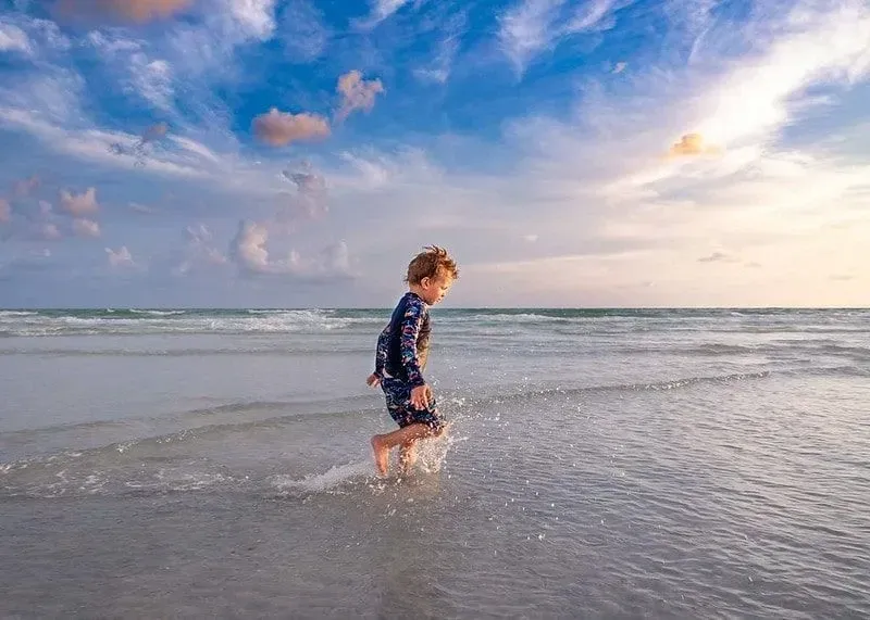 A young boy running on a beach on holiday. Image