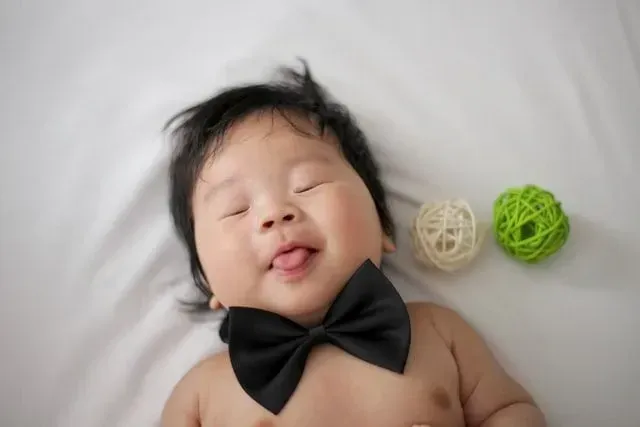 An adorable newborn baby boy wearing a black bow