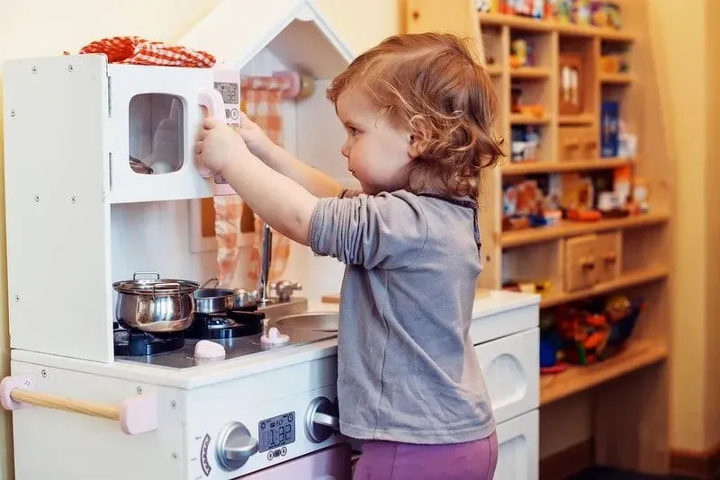 Little girl playing cooking in her mini kitchen.