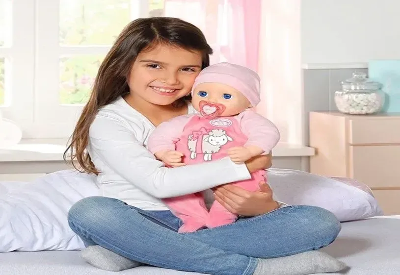 Girl holding doll while sitting in the bed.