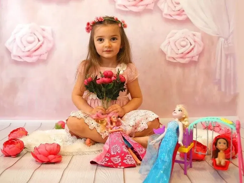 Girl in pink dress playing dolls.