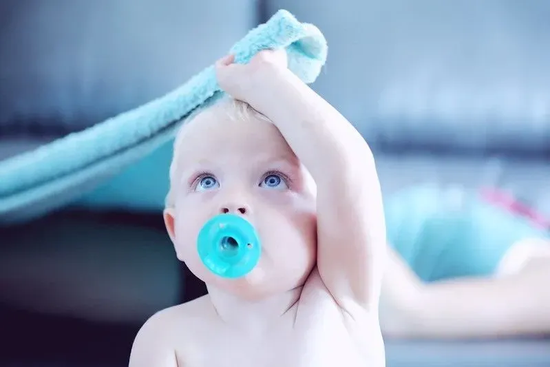 Baby with bright blue dummy. 