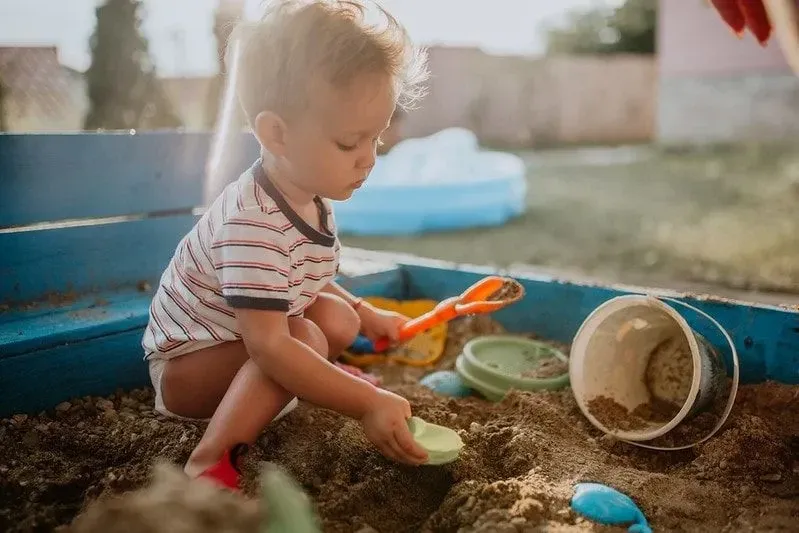 Child playing in sandpit outside having fun. 