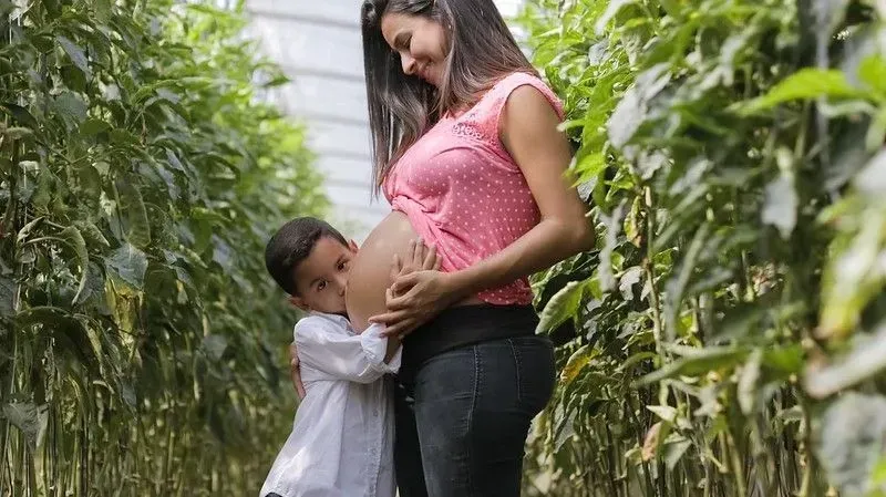 Pregnant mum in maternity jeans, with child.